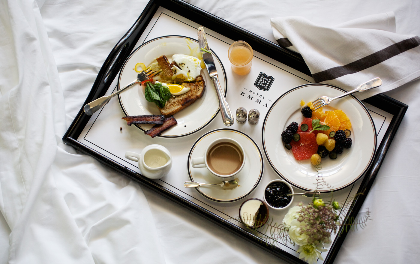 Picture of breakfast in bed with coffee, fruits and toast. One of the culinary options available at the hotel emma.